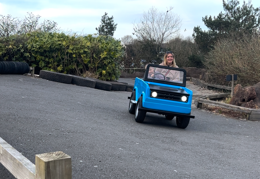 Parent and child smiling whilst using Adventure-Trukz, an electric ride-on attraction at Haven
